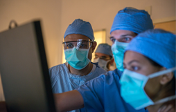 doctors in masks looking at a screen